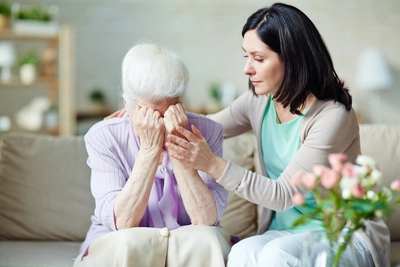 Woman supporting an elderly woman emotionally.